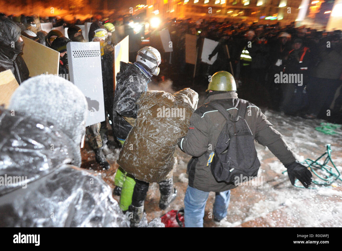 January 26, 2014 - Kiev, Ukraine: A wounded protester is being taken away by fellow demonstrators after being hit by a police water cannon near Independence Square. This part of Kiev's city center was devastated after heavy clashes between protesters burning tyres and police forces using water cannon in freezing temperatures  Un manifestant est evacue apres avoir ete touche par par le canon a eau d'un camion policier. Les temperatures sont si glaciales que l'eau gele quasi instantanment et le manifestant est donc compltement transi de froid en quelques secondes. Des barricades ont ete erigees Stock Photo