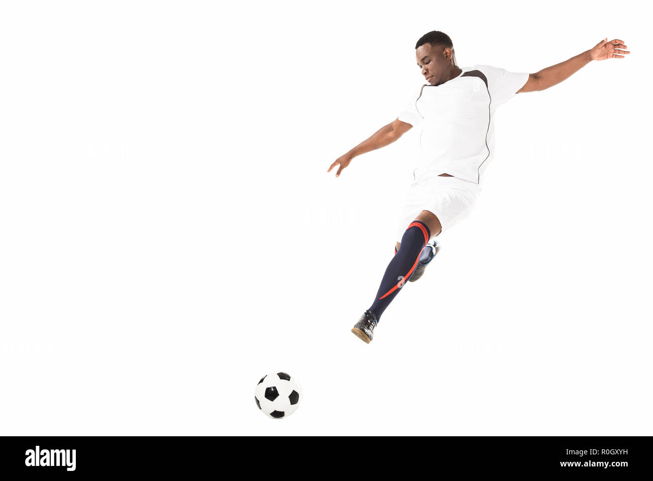 young african american soccer player kicking ball in jump isolated on ...