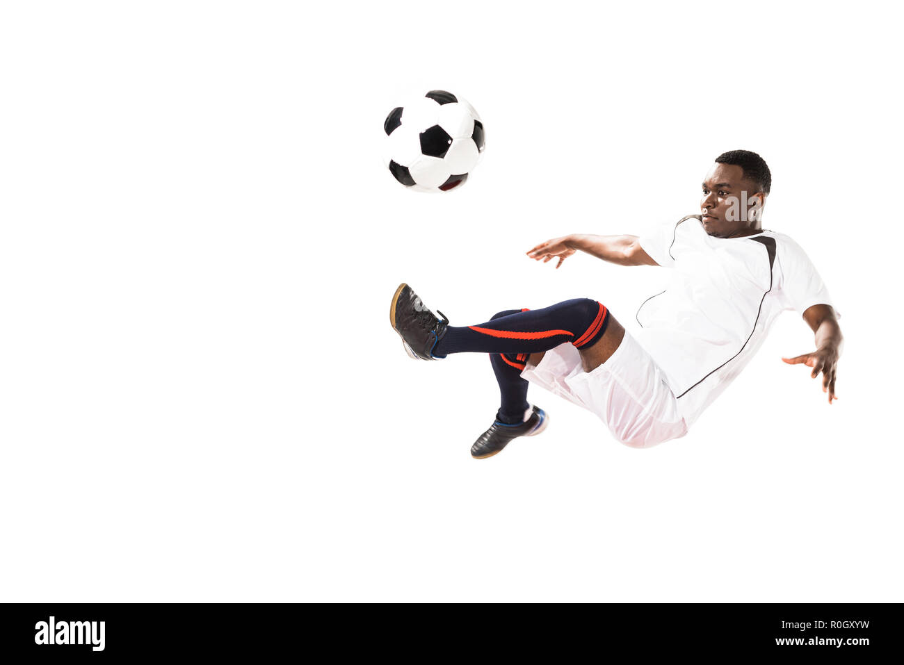 athletic young african american soccer player kicking ball in jump ...