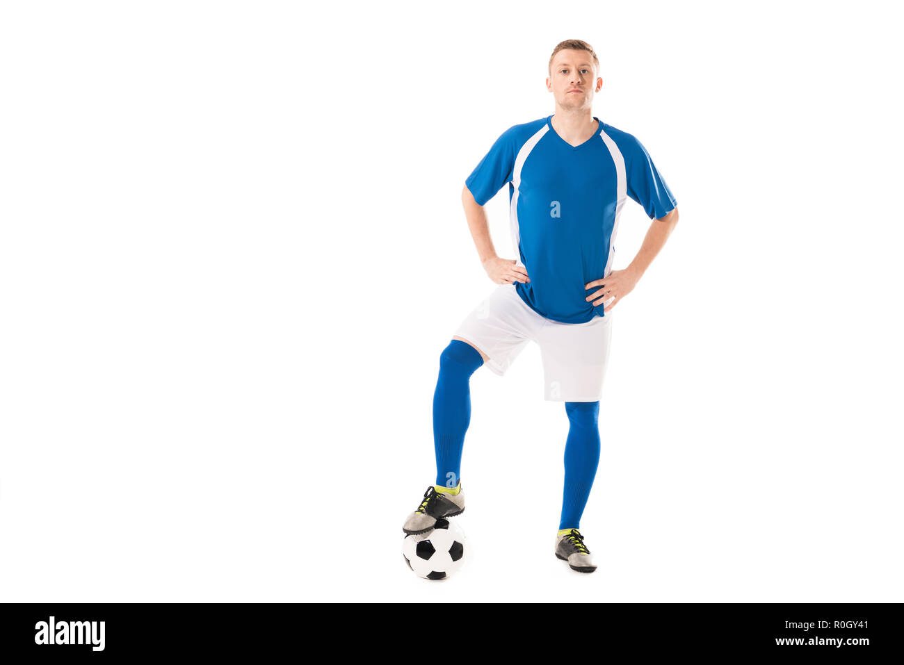 confident young soccer player standing with hands on hips and looking