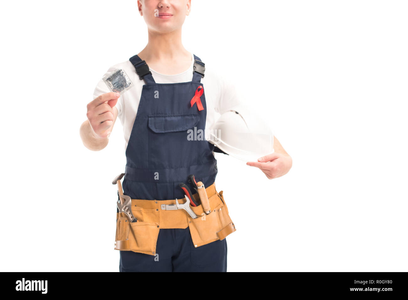 cropped image of worker in uniform and red ribbon holding helmet and condom isolated on white, world aids day concept Stock Photo