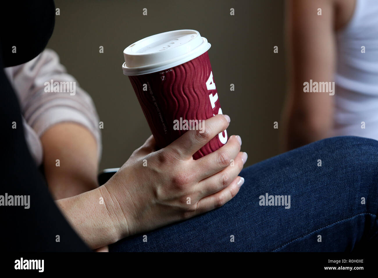 A lady holding a Costa Coffee take-away cup on her lap in London, UK. Stock Photo