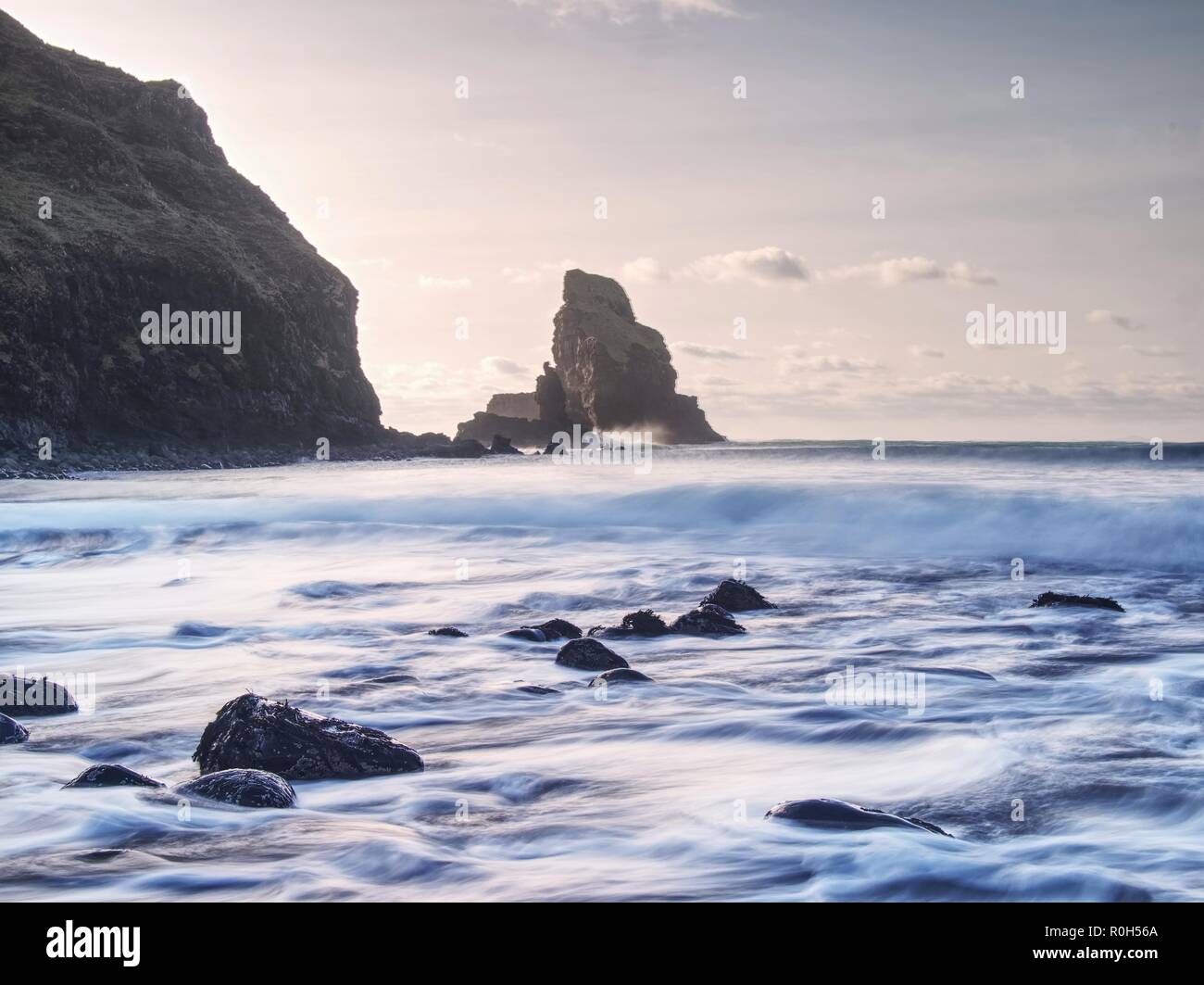 Evening Bay. Sharp rocks, black rounded boulders, stony beach, sand and ...