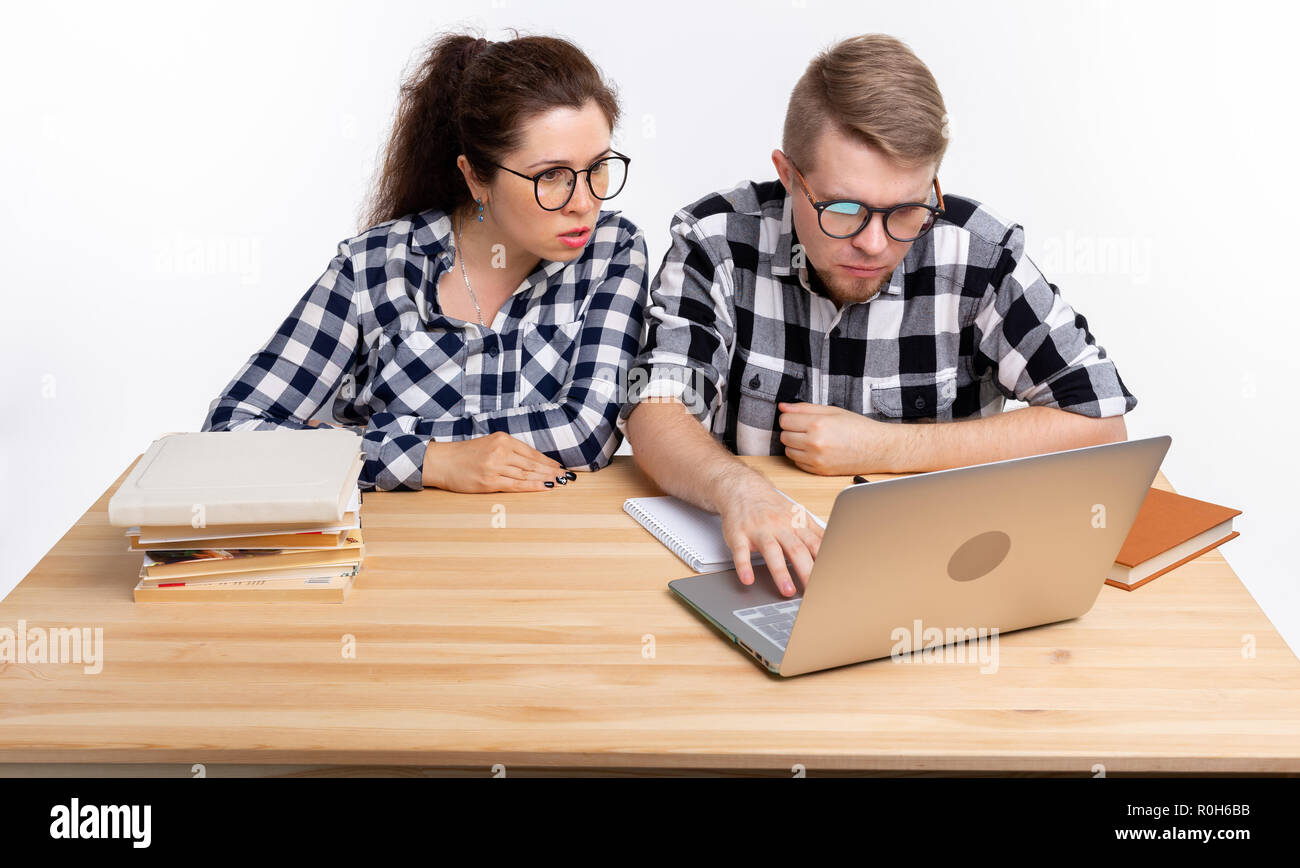 People and education concept - Two puzzled students in plaid shirts sitting at table Stock Photo