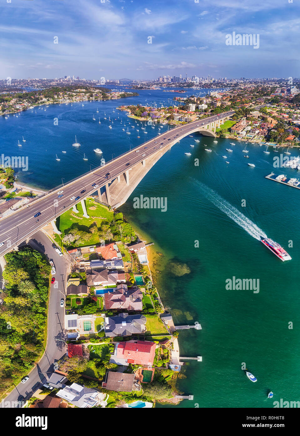 Calm waters fo Parramatta river flowing between Inner West suburbs of Sydney connected by Gladesville bridge in view of distant city CBD skyline. Stock Photo