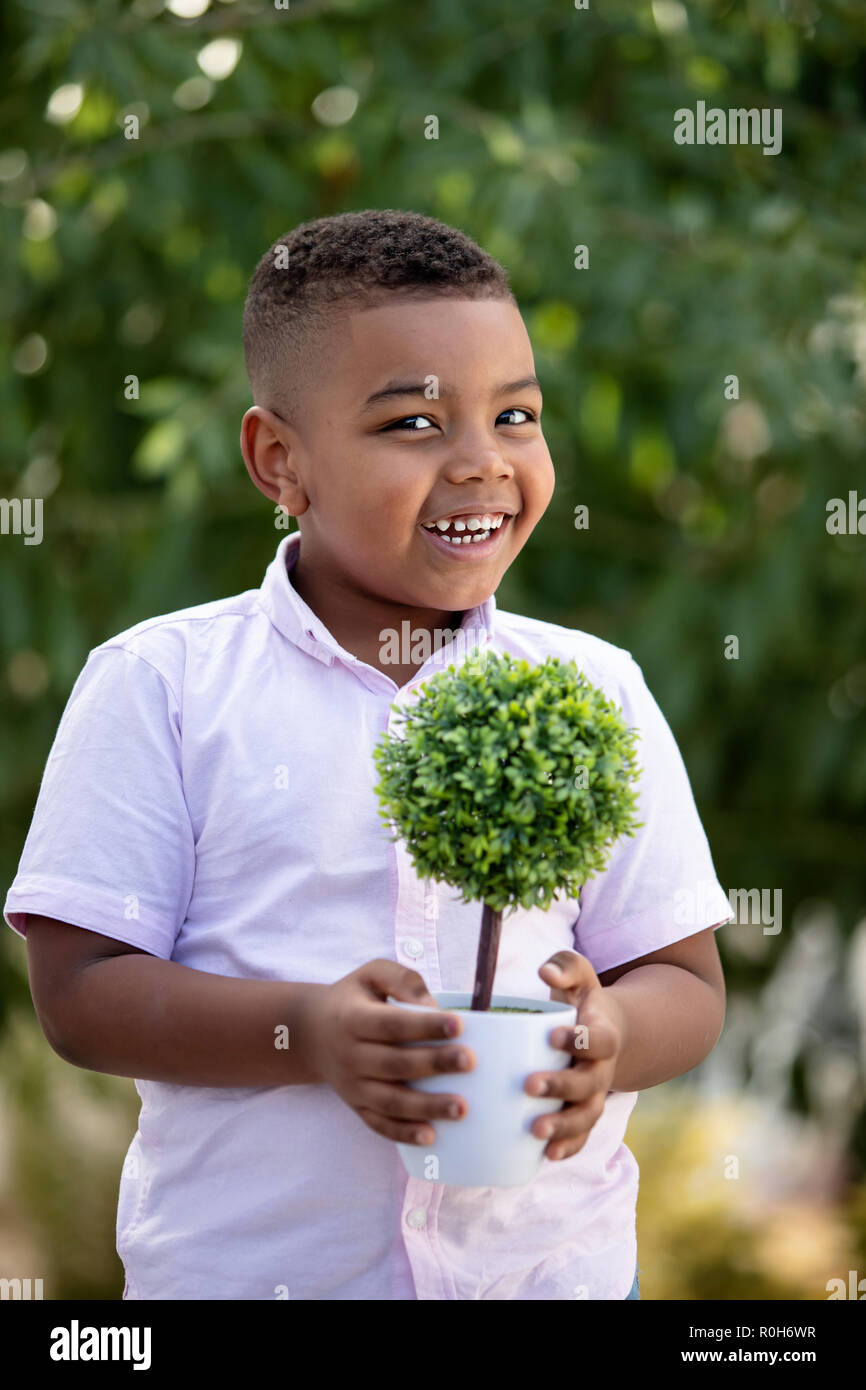 Happy latin child with a small tree in the garden Stock Photo