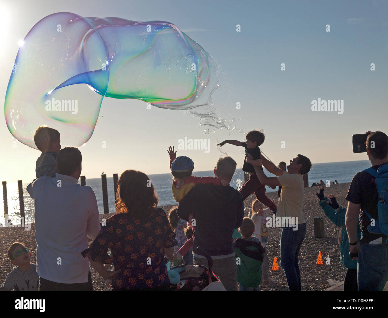 Large bubbles being blown for the amusement of children on the beach at