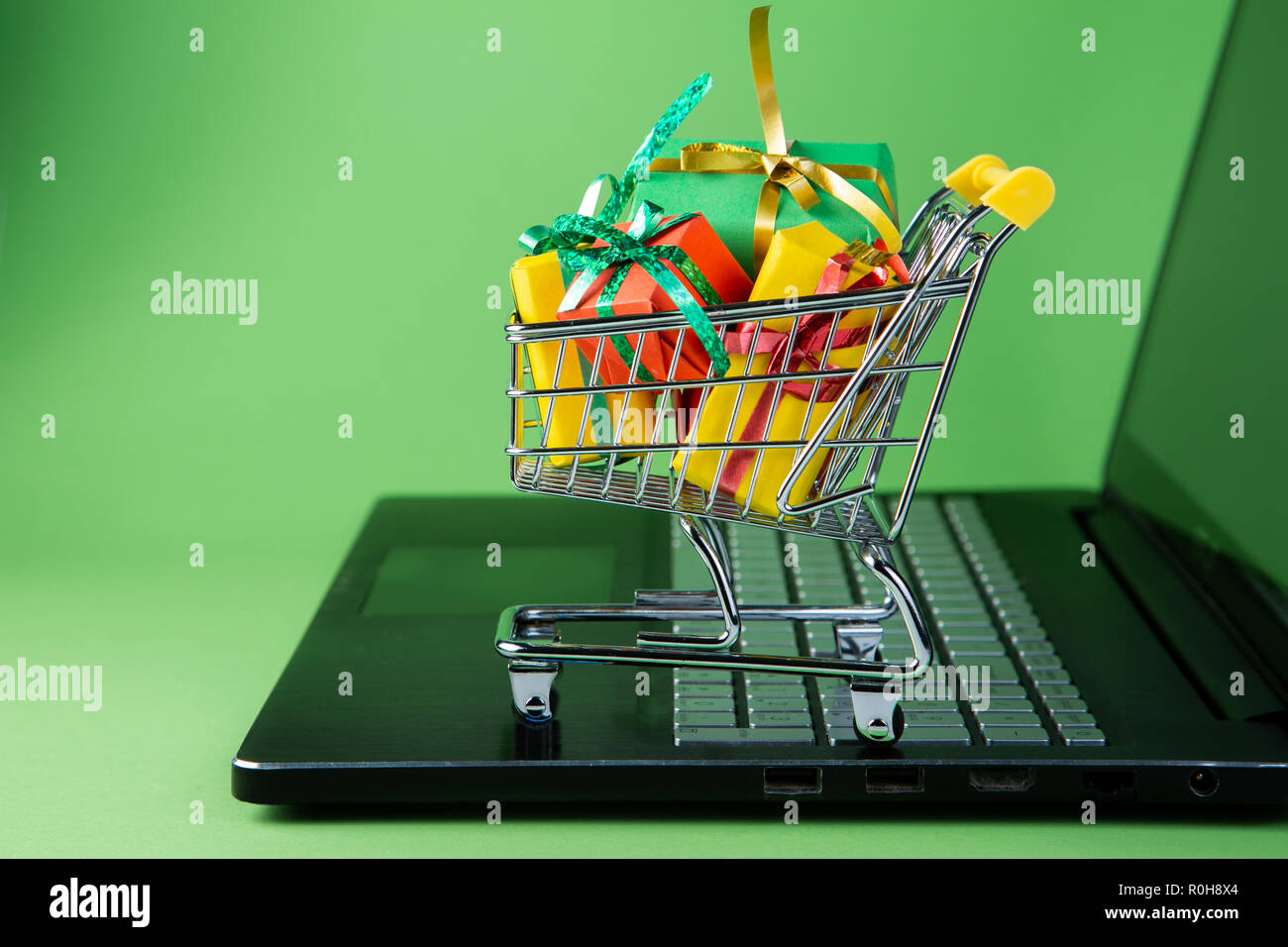 Ciber monday concept - trolley cart with christmas presents on notebook Stock Photo