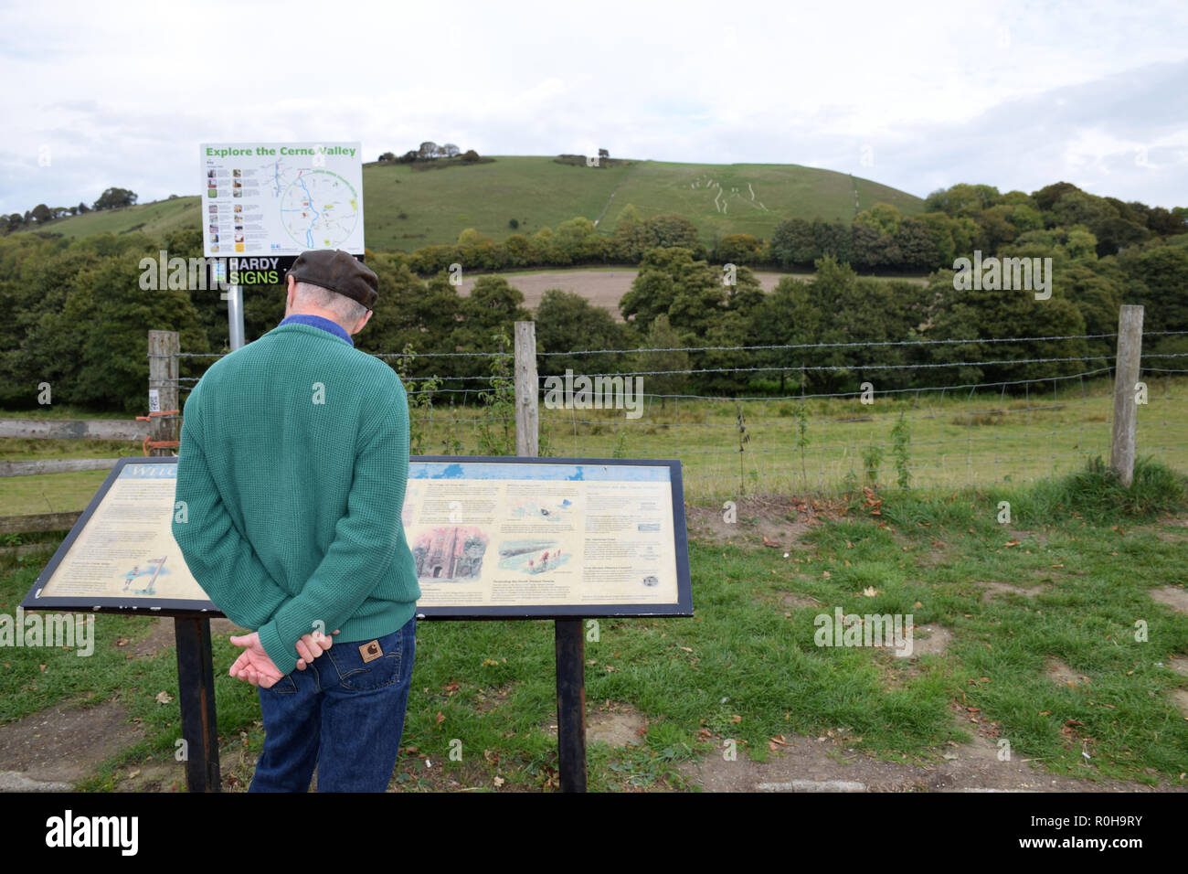 Tourist looking at Cerne Abbas Giant information sign, Dorset, UK ...