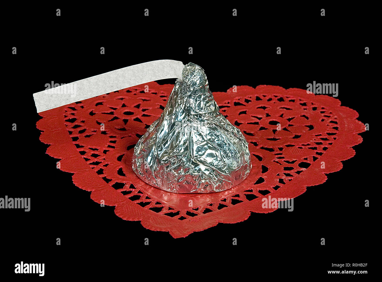 silver foil wrapped candy kiss with blank paper tag on red lace heart