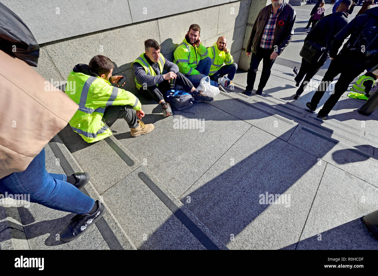 Workmen having a break on the steps of Trafalgar Square, London, England, UK. Stock Photo