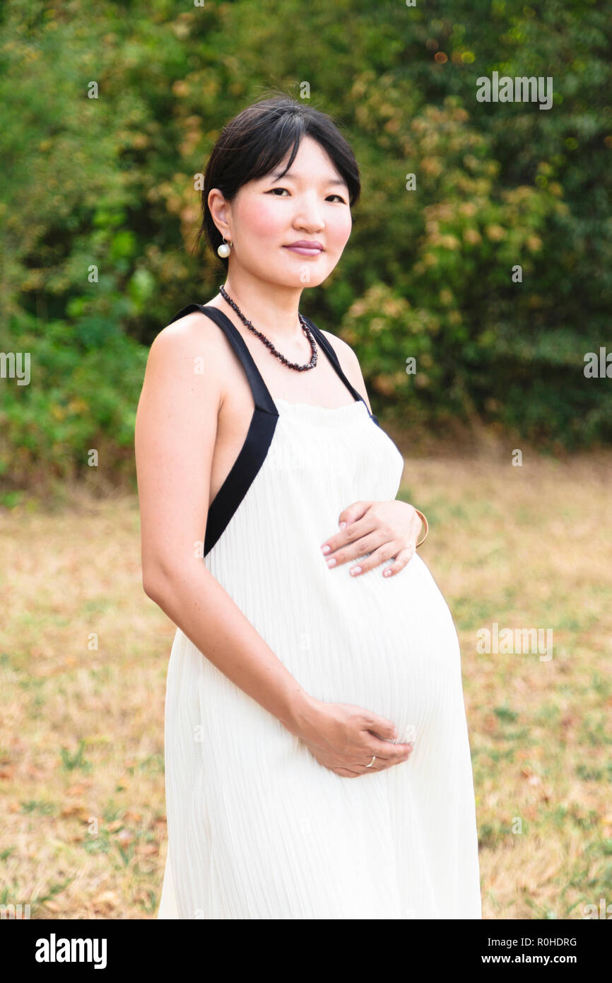 Beautiful pregnant asian woman in park in warm summer day Stock Photo