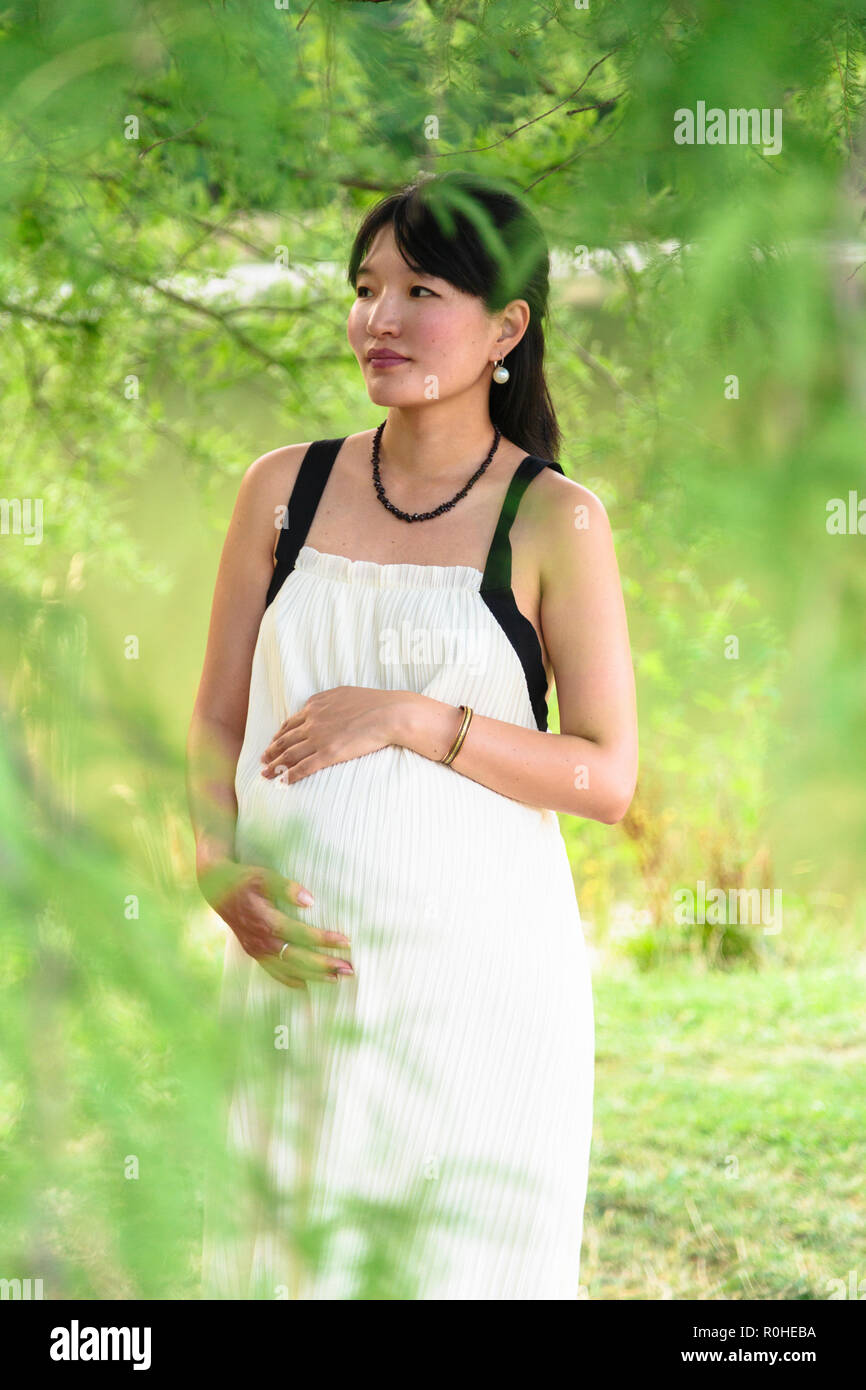 Happy pregnant woman smiles and hugs her belly outdoor Stock Photo - Alamy