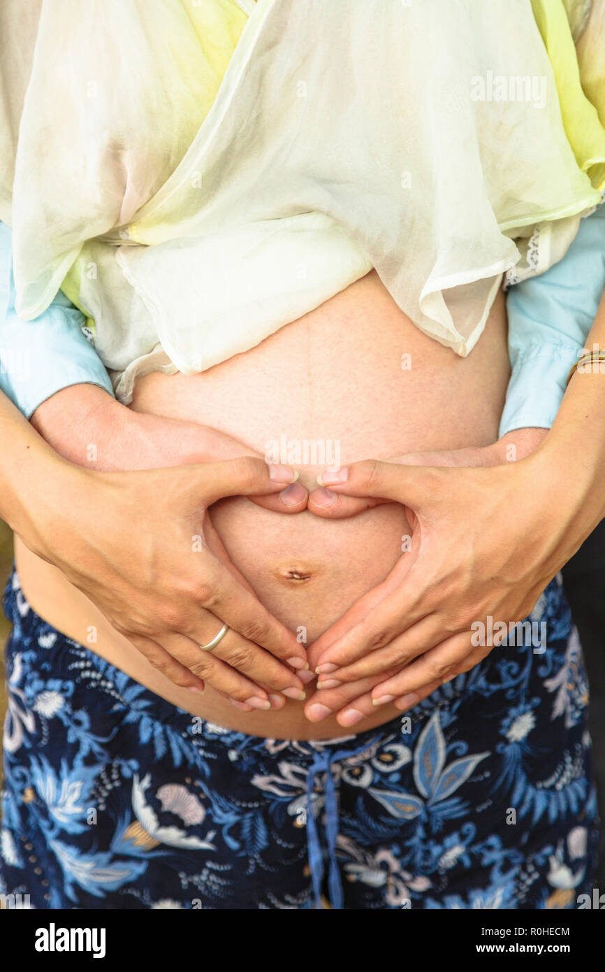 Four arms show heart on stomach of pregnant woman Stock Photo - Alamy
