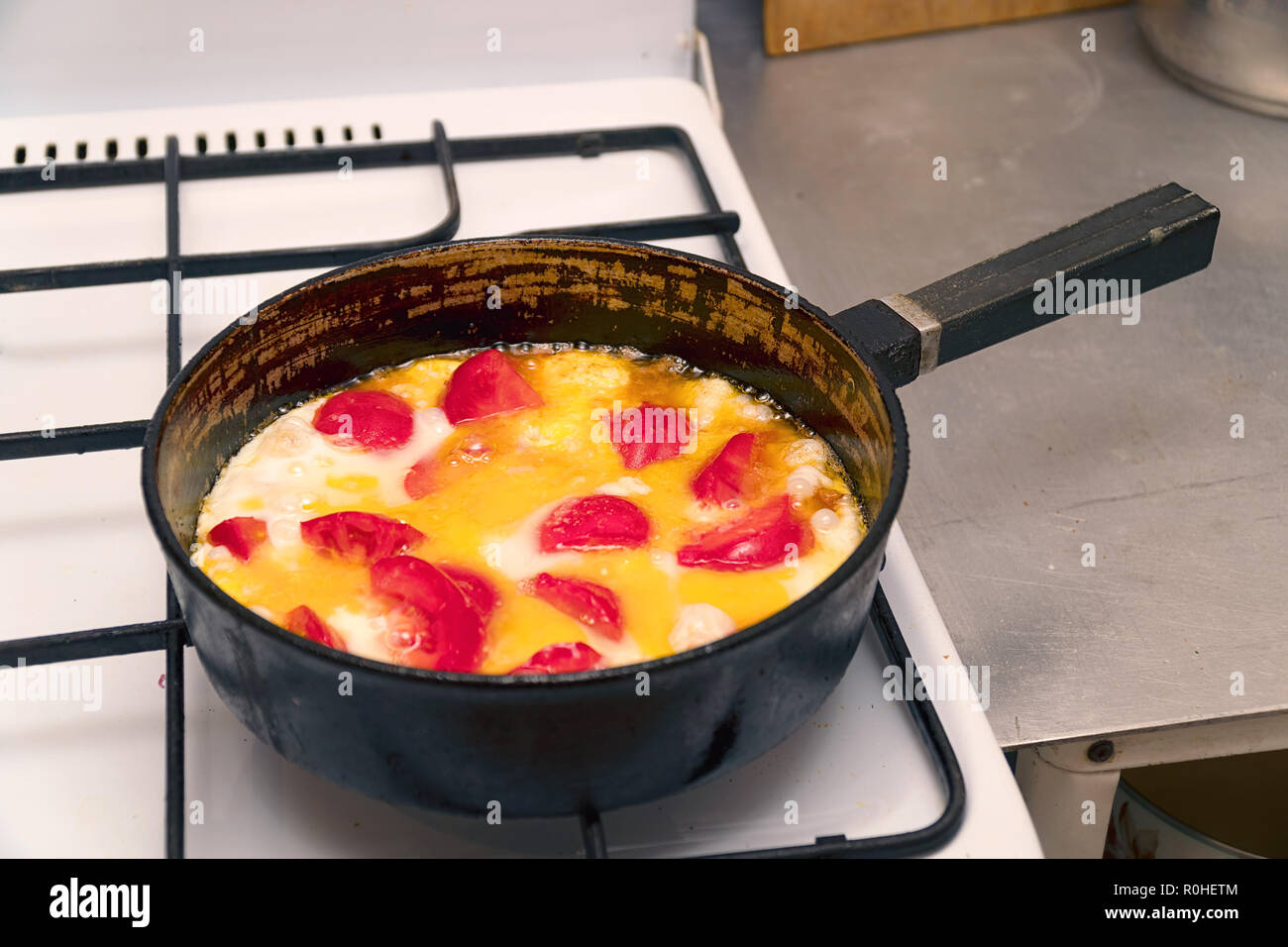 Fried eggs with tomatoes in a pan on gas stove Stock Photo Alamy