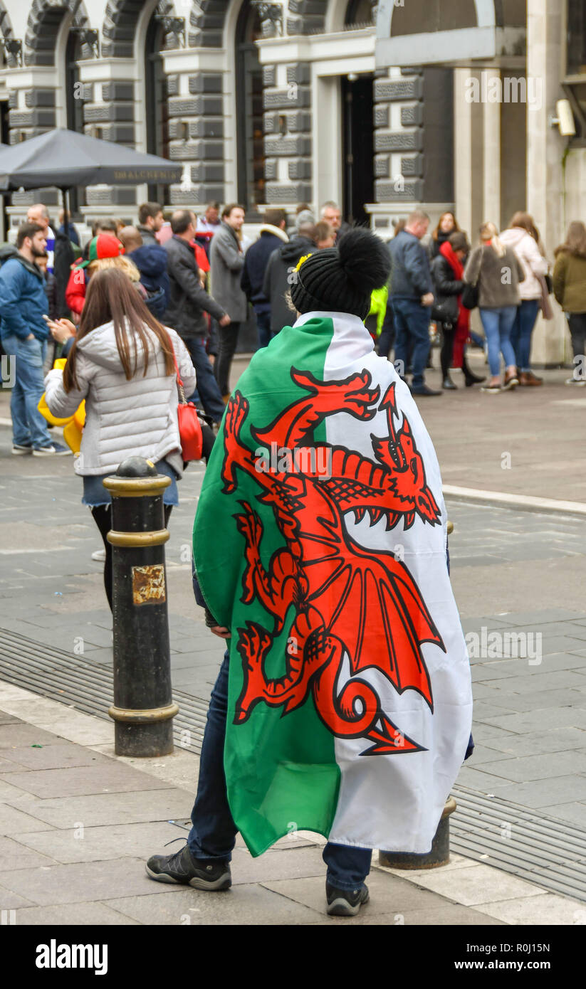 CARDIFF, WALES - NOVEMBER 2018: Person with a Welsh flag, the 'Red Dragon', draped over her shoulders in Cardiff city centre on the day of an internat Stock Photo