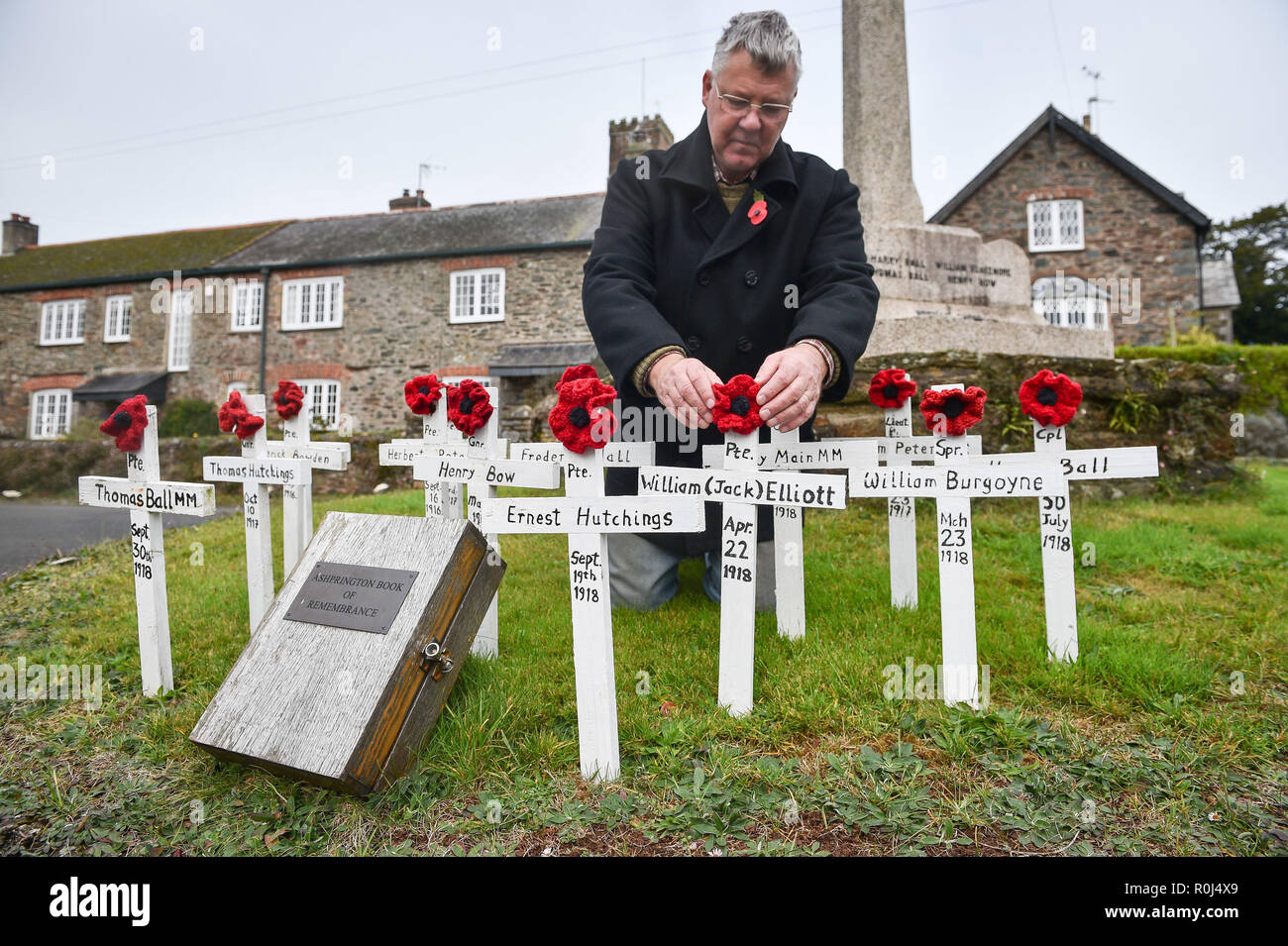 Local councillor Laurence Green tends to hand-made wooden crosses and hand-knitted poppies, which are placed on the war memorial in the Devonshire village of Ashprington, where he has adorned the small memorial with crosses of those that died in the Great War from the Ashprington Parish. Villagers tend the memorial and have made a book featuring details of parishioners that served and died during the First World War. Stock Photo