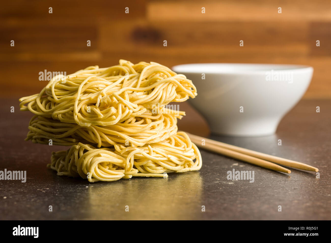 Uncooked instant chinese noodles on old kitchen table. Stock Photo