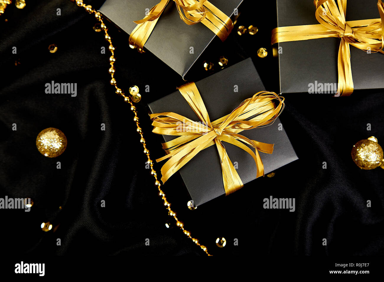Luxury black gift boxes with gold ribbon on shine background. Christmas