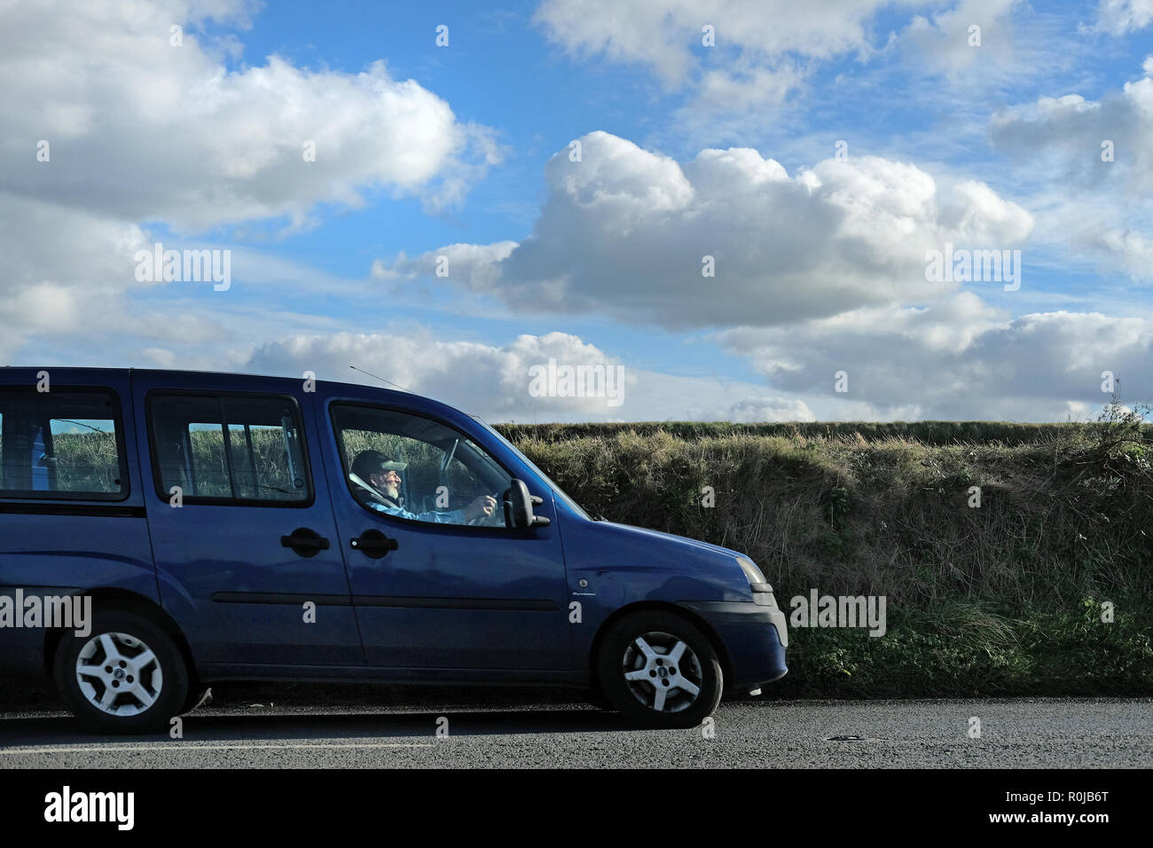 An older man driving along a country road past fields in Cornwall, UK. Stock Photo