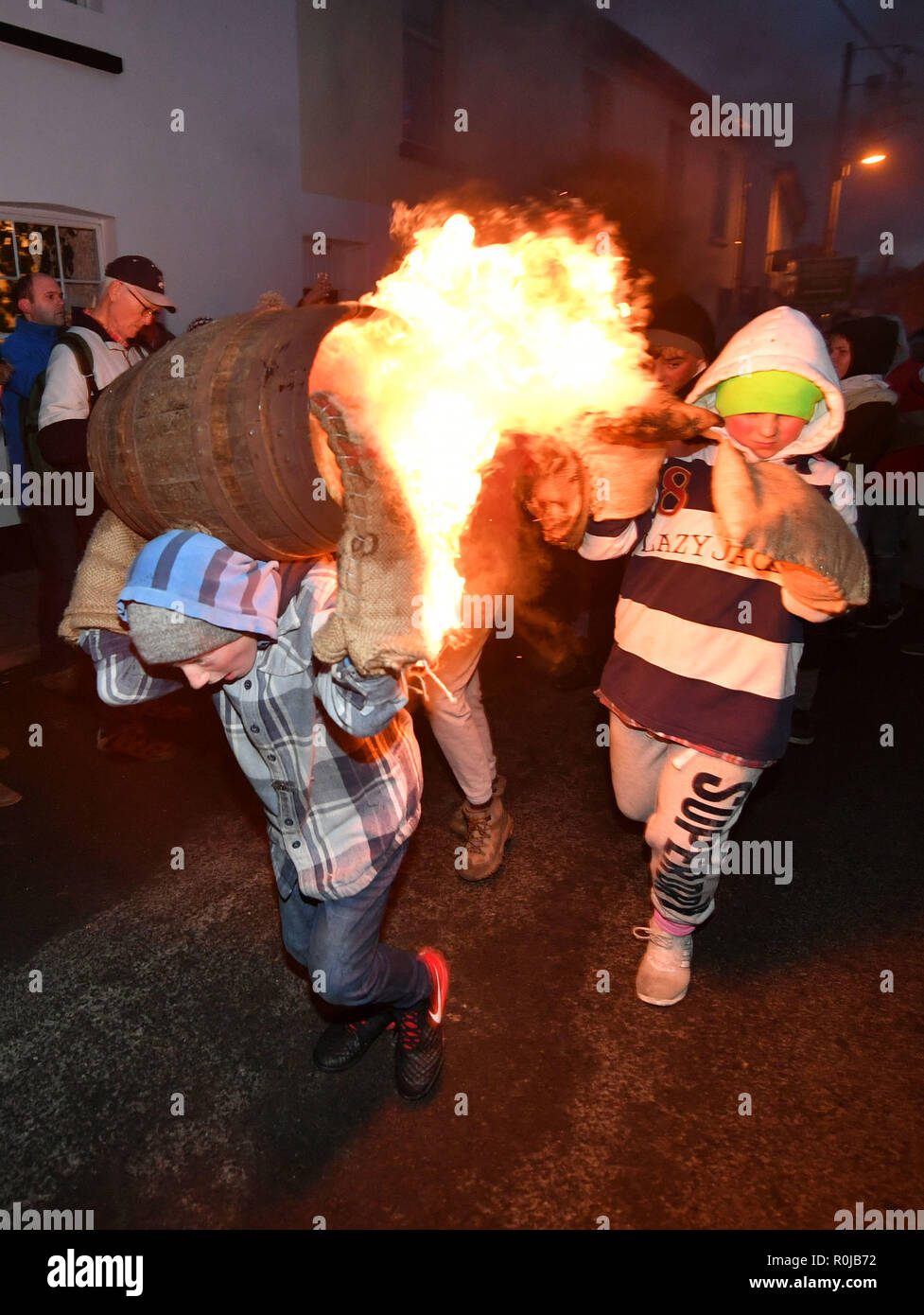 Children from the village of Ottery St Mary in Devon carry the traditional burning tar barrels through the streets of the village on bonfire night. Stock Photo