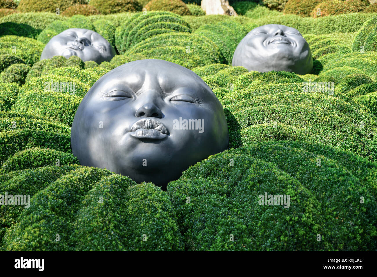 ETRETAT, FRANCE - SEPTEMBER 02, 2018: Giant rubber heads sleeping on green pillows. Boxwood garden in the famous garden of Etretat, Normandy, France Stock Photo