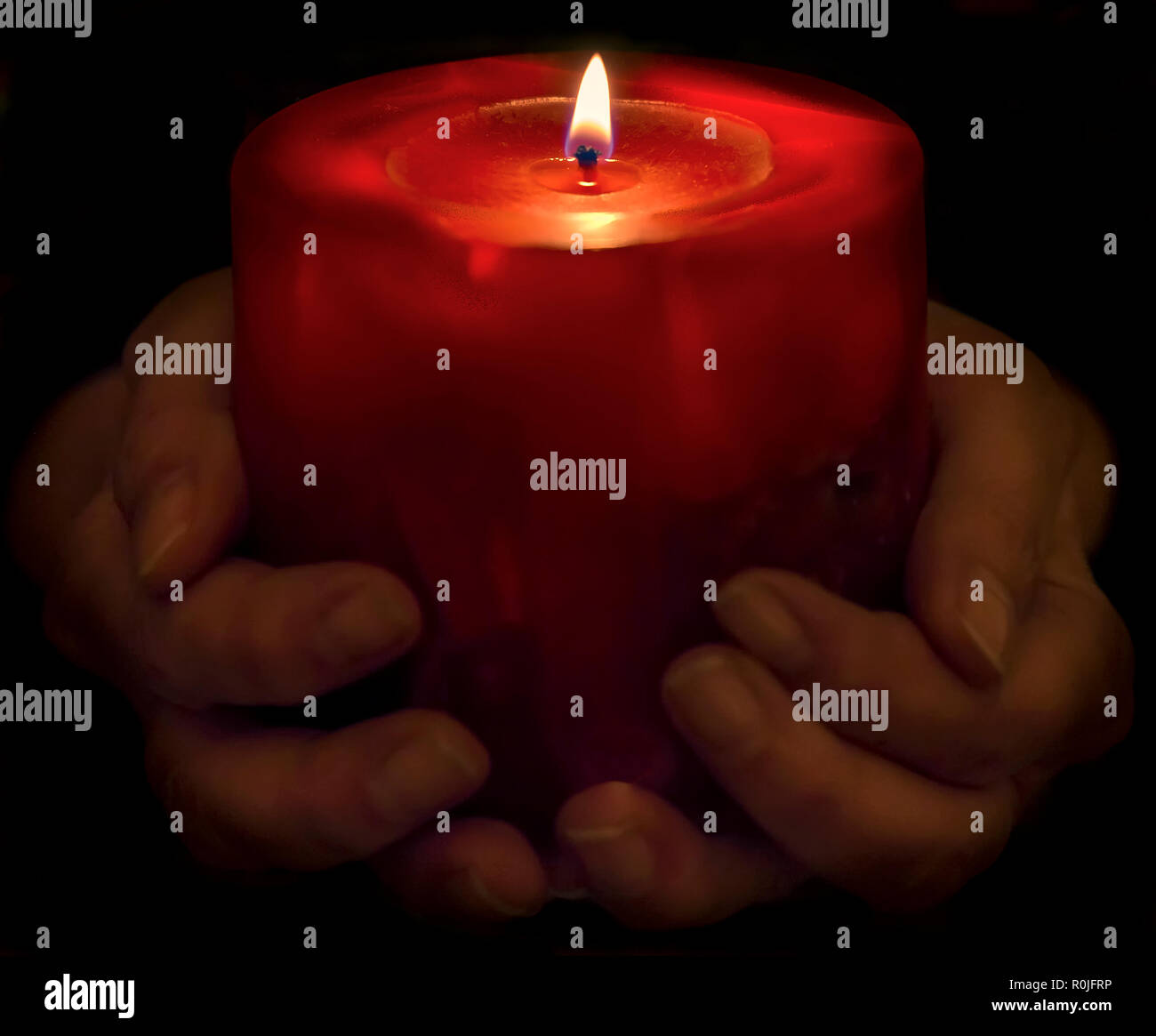 Beautiful red Christmas candle lit in a dark atmosphere, supported by