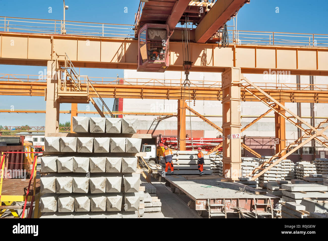 Tyumen, Russia - August 13, 2013: Finished goods warehouse at Concrete Goods Plant No. 5. Slinger with crane operator work on concrete products loadin Stock Photo