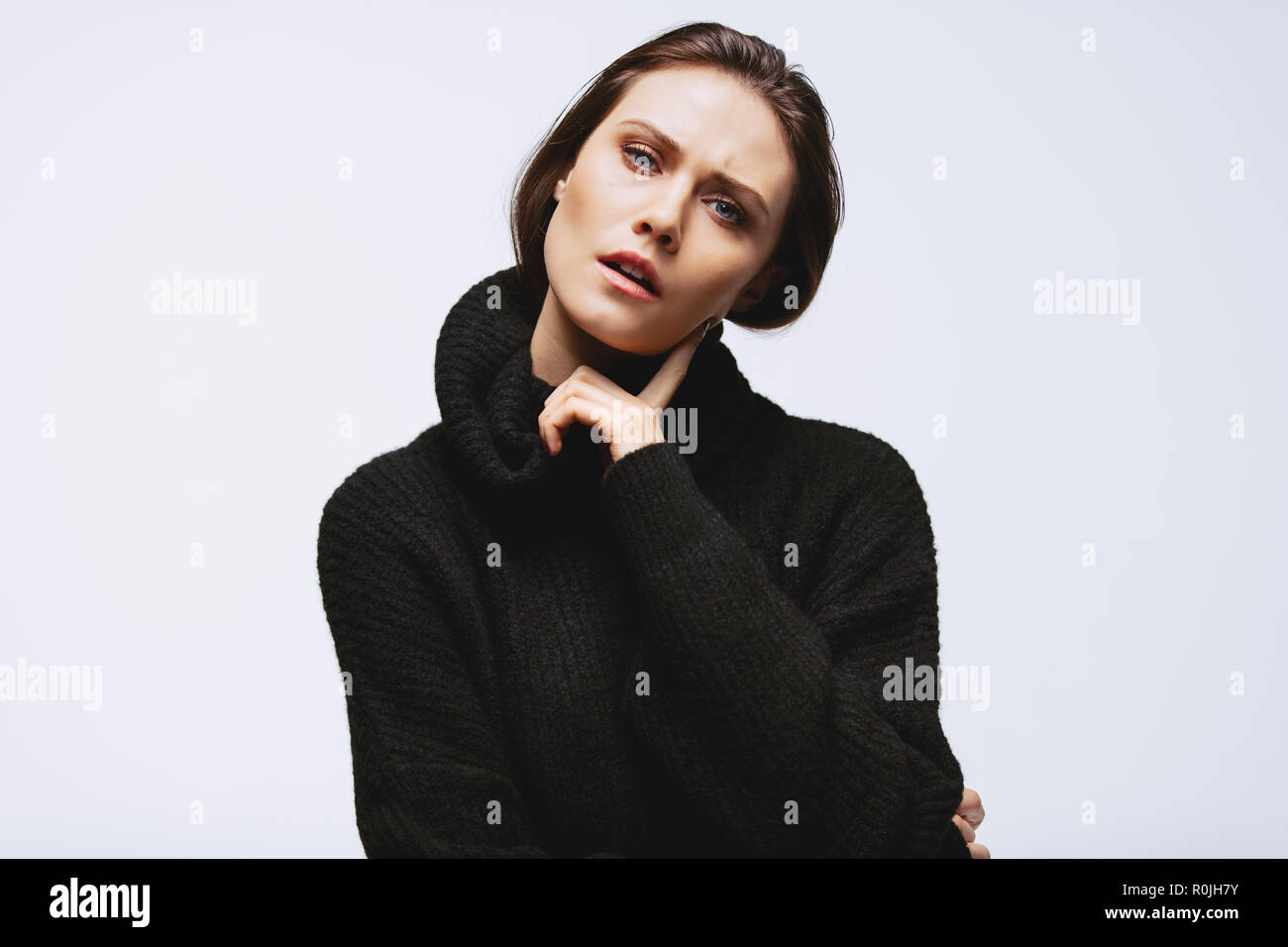 Portrait of young woman in black cardigan with finger on cheek. Caucasian female model staring at camera. Beautiful caucasian female with thoughtful f Stock Photo