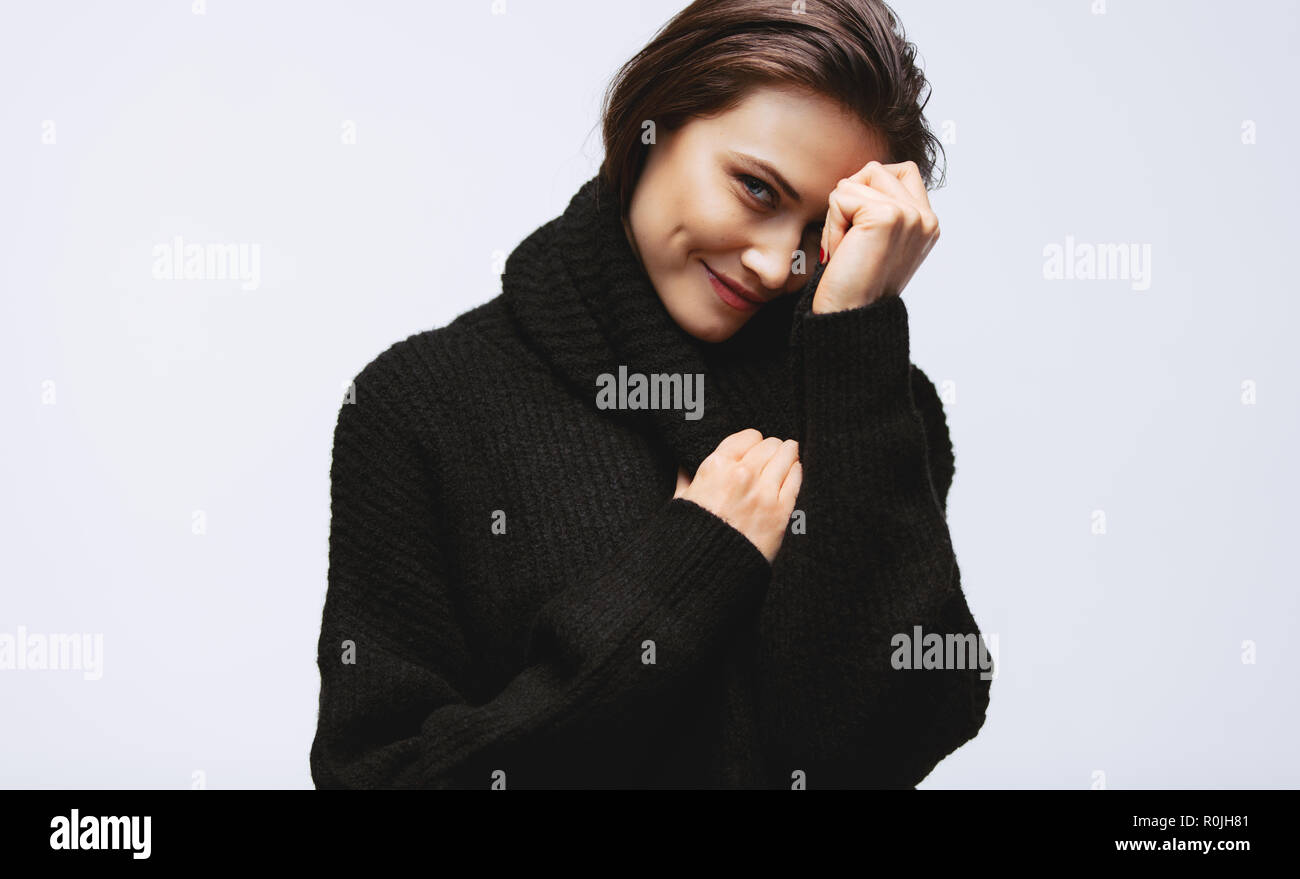 Portrait of pretty woman looking at camera and smiling. Female model in black sweater on white background. Stock Photo