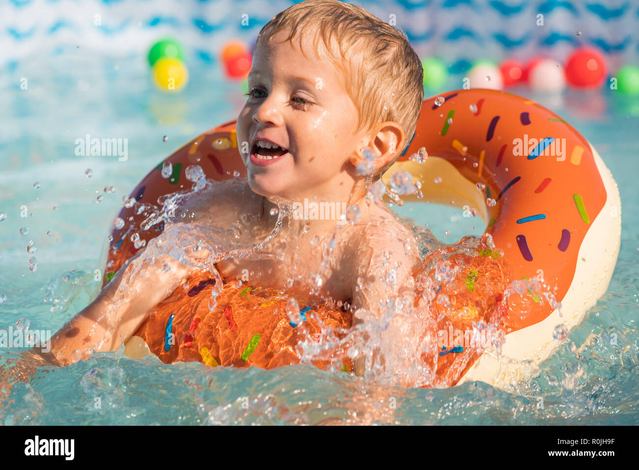 Happy little boy playing with colorful inflatable ring in outdoor