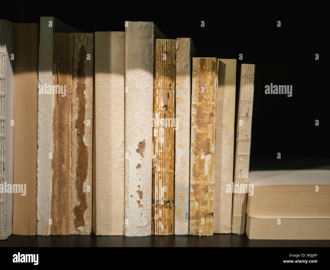 Old, worn out books standing on a black book shelf Stock Photo - Alamy
