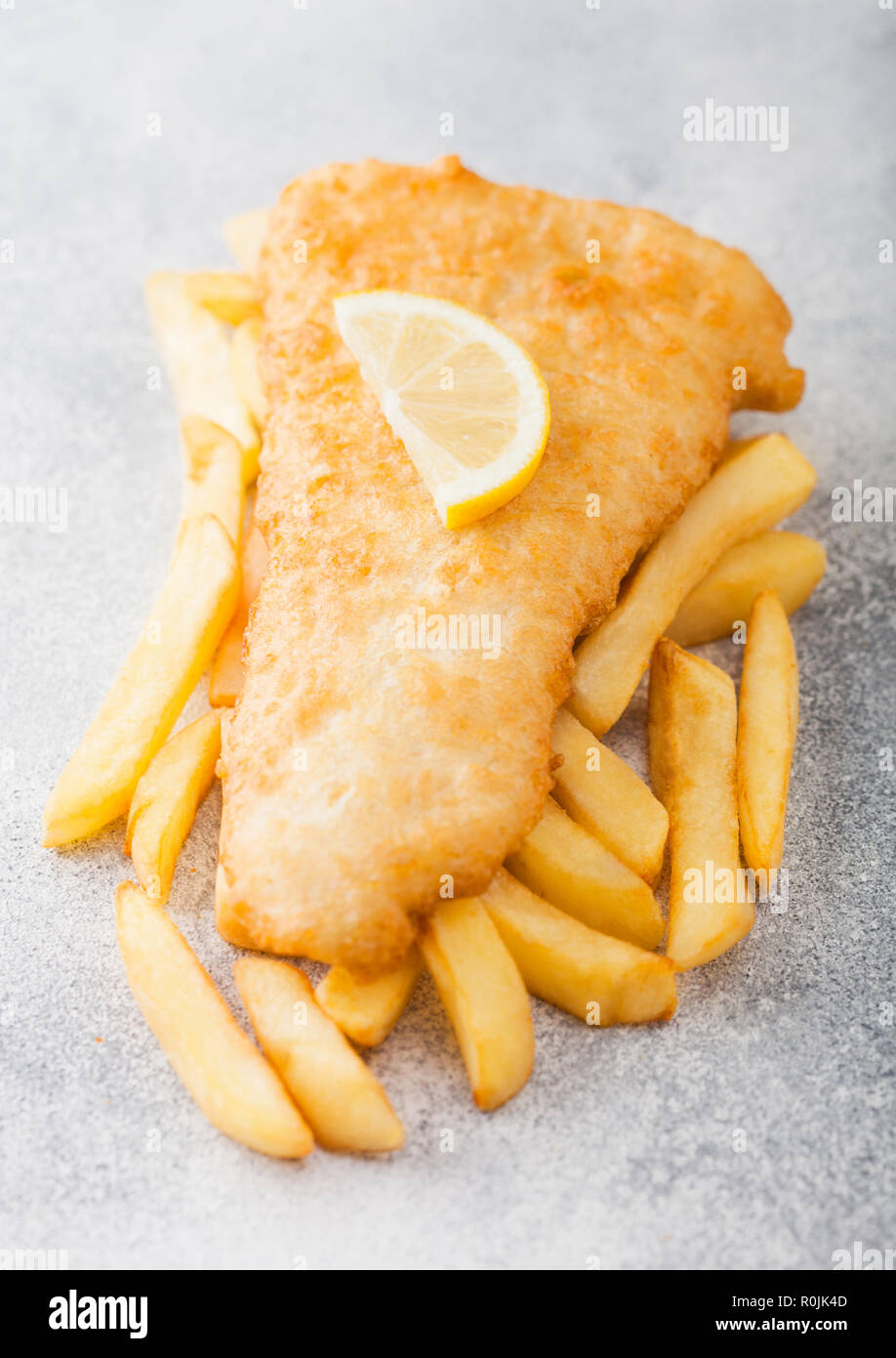 Traditional British Fish and Chips with lemon slice on white stone background. Stock Photo