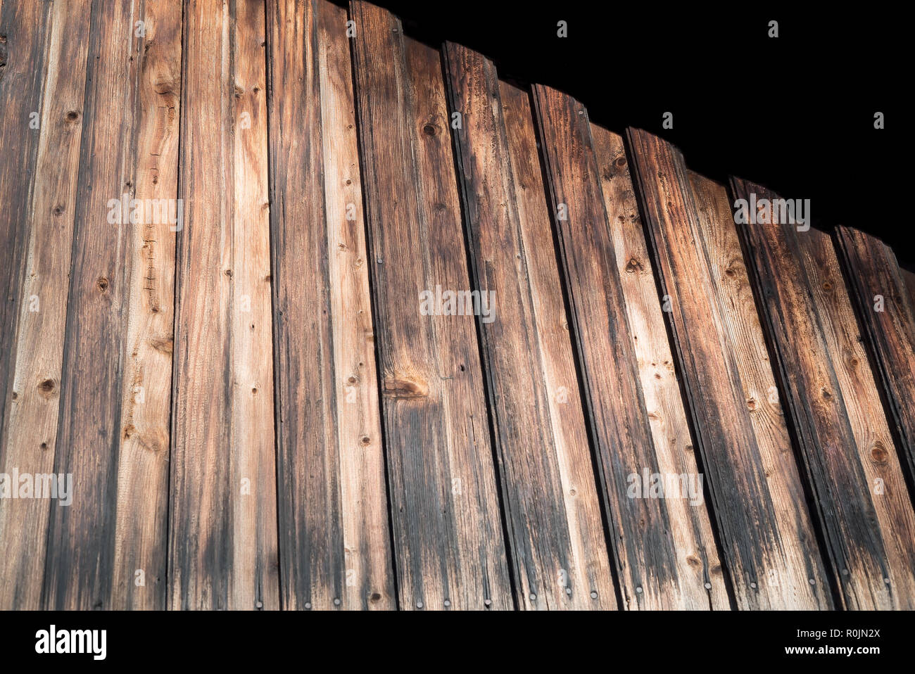 Weathered rustic wood wall with old antique varnish on the rough, vintage surface - Tall rural blockade - Aged wooden background. Stock Photo