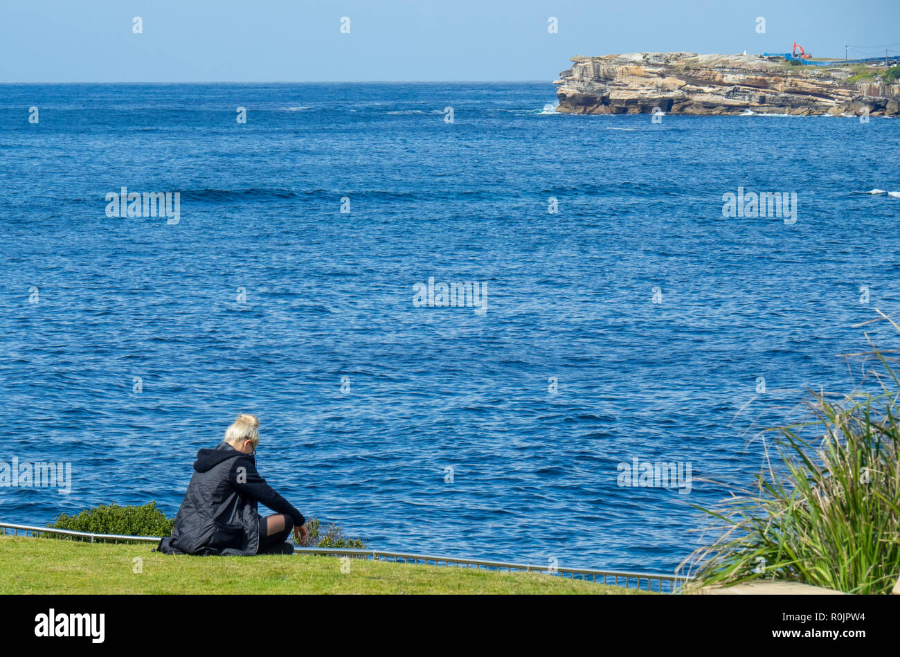 Caucasian middle age man sitting at the edge of Dolphins Point staring out to Pacific Ocean Sydney NSW Australia. Stock Photo