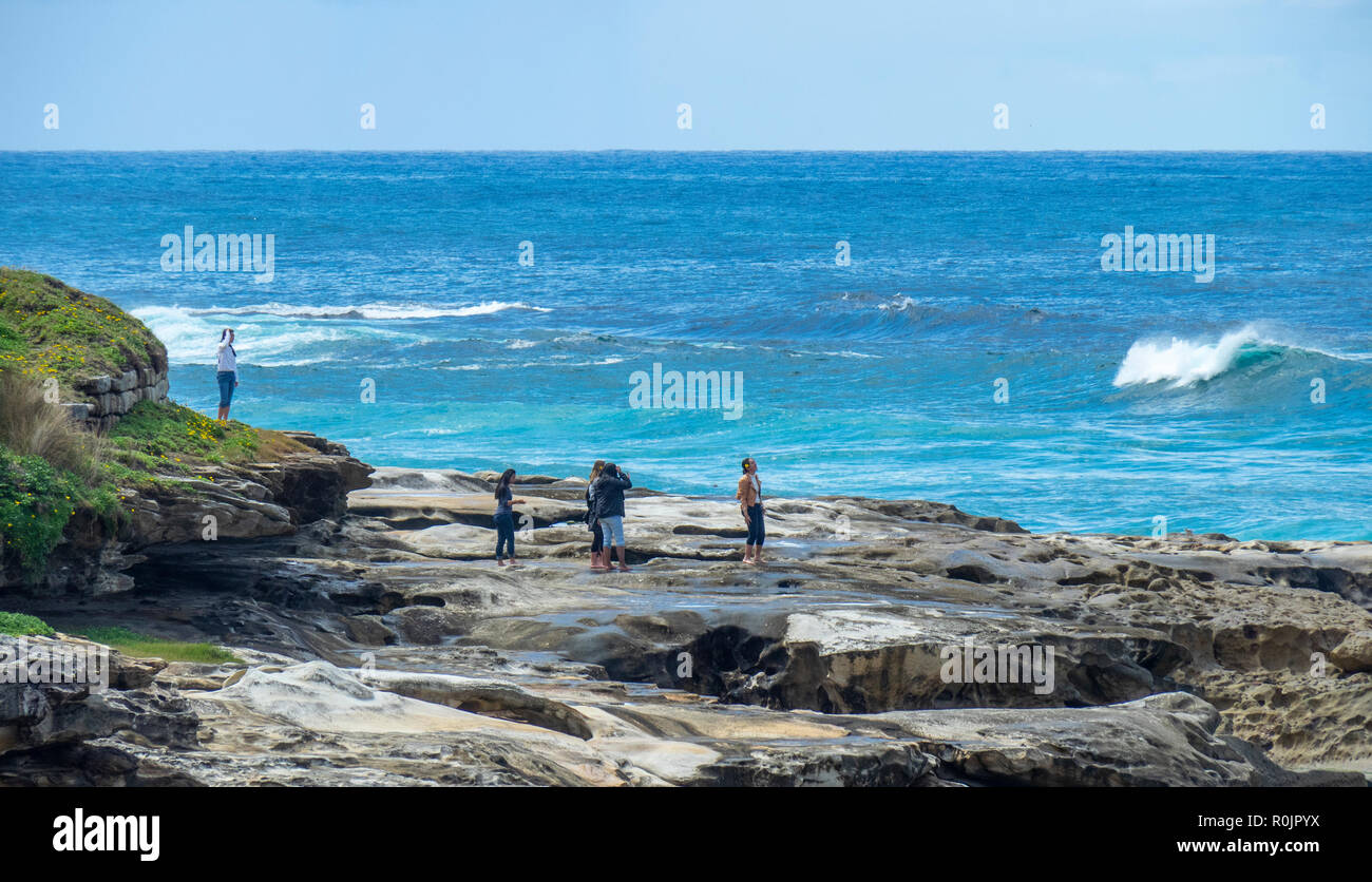 Bondi to Coogee coastal walk people standing on sandstone rocks over Pacific Ocean Sydney NSW Australia. Stock Photo
