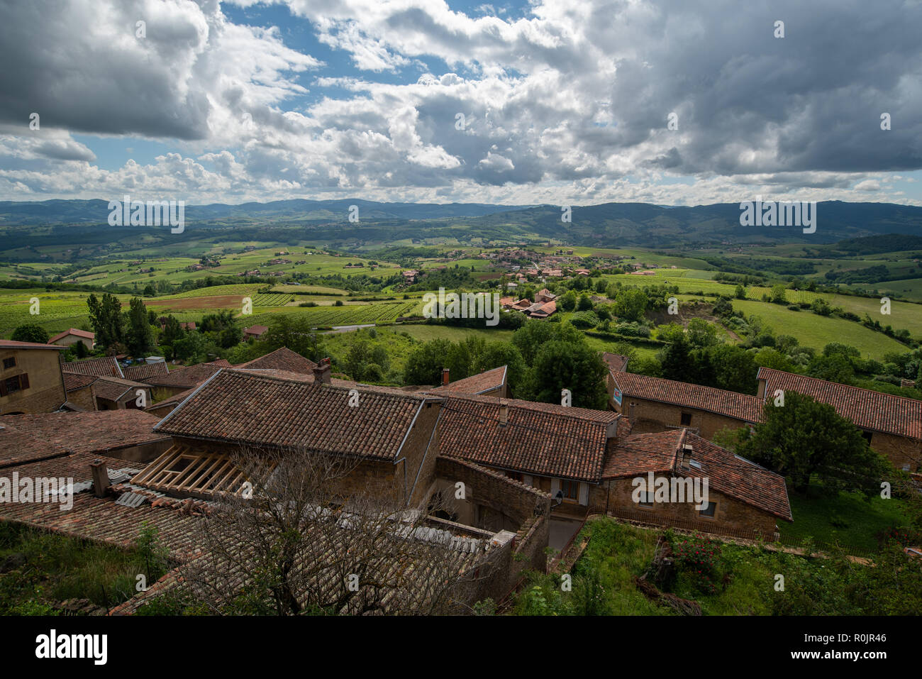 The Beaujolais wine growing landscape in France nestles under a dramatic cloudy sky, as viewed from the top of small picturesque village of Oingt. Stock Photo