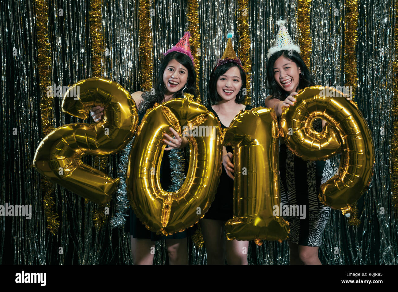 girls carrying gold colored numbers 2019 balloon showing to camera smiling attractive. young ladies celebrating new year countdown at nightclub. asian Stock Photo