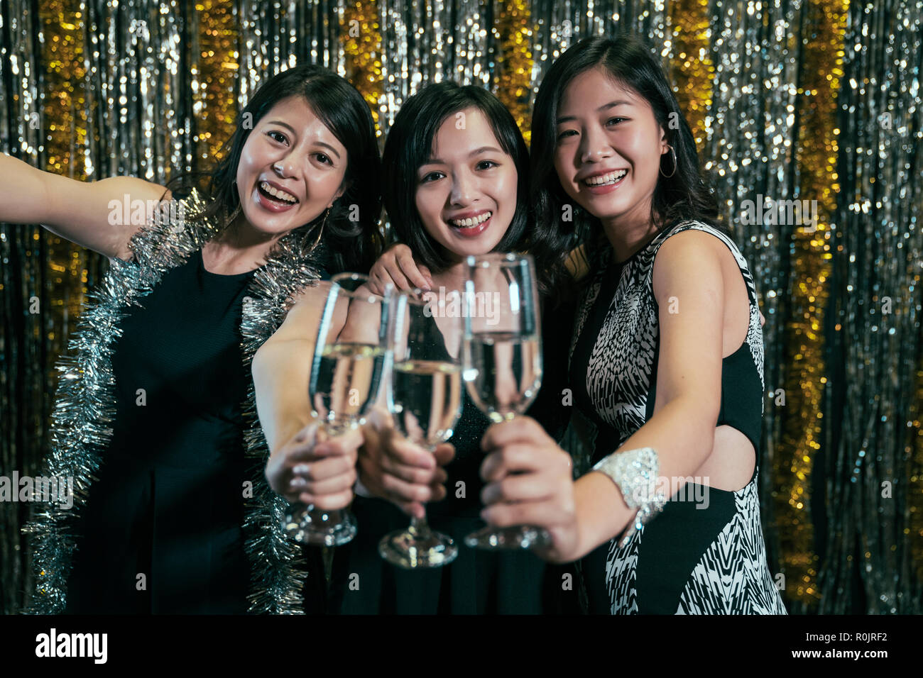 attractive women with fashion clothes having fun in nightclub. young ladies holding alcohol celebrating in club. girls night out cheer champagne to ca Stock Photo