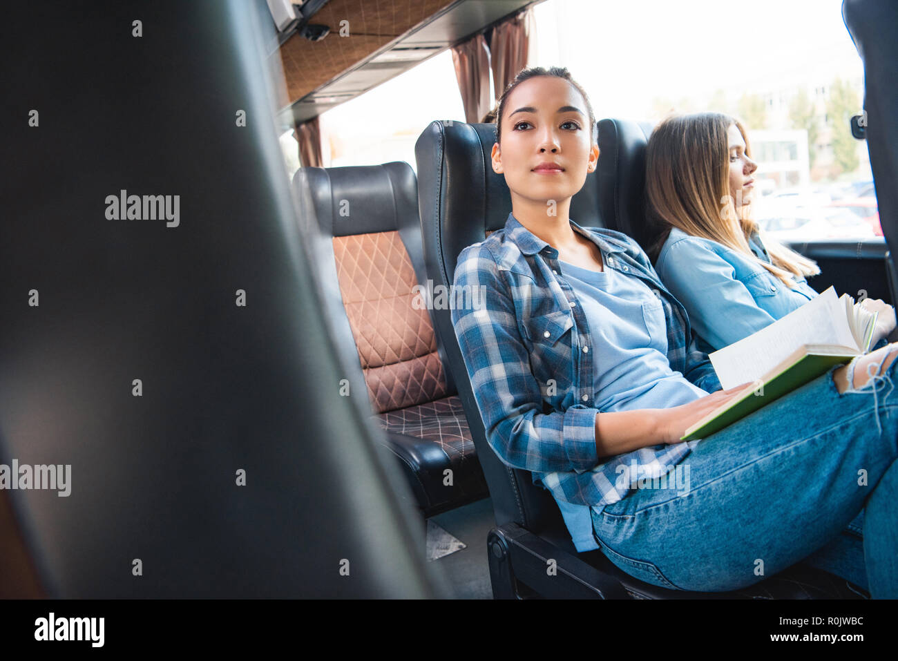 attractive asian woman reading book while her female friends sitting near  during trip on travel bus Stock Photo - Alamy