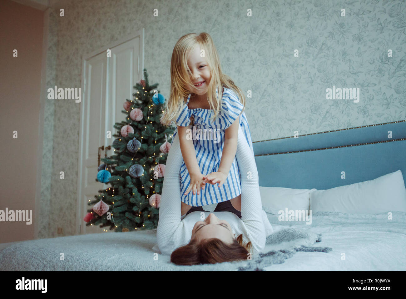 mother playing with little girl on bed at home Stock Photo