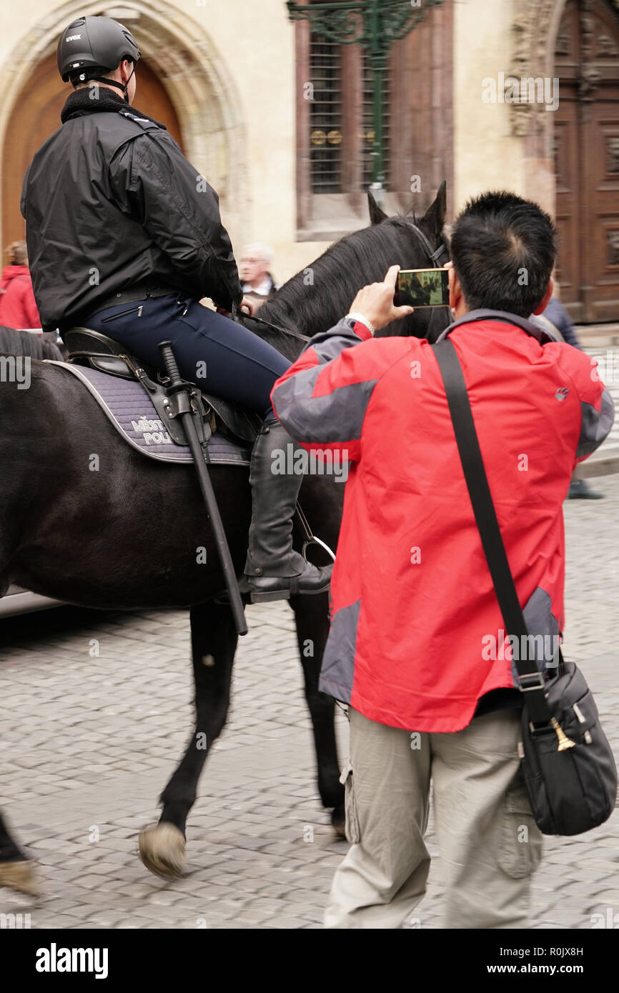 An Asian tourist photographs a policeman in the old town of Prague Stock Photo