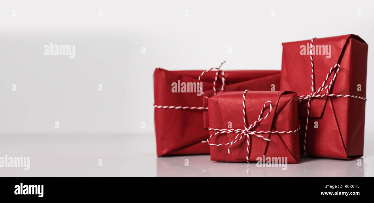 Christmas gift boxes wrapped in red paper and bow of dtriped rope on ...