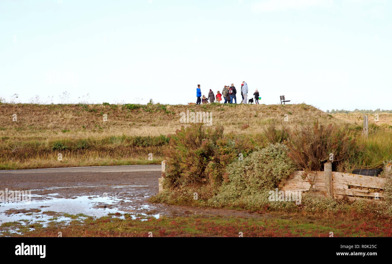 A group of people walking on the Norfolk Coast Path on the floodwall at Thornham, Norfolk, England, United Kingdom, Europe. Stock Photo