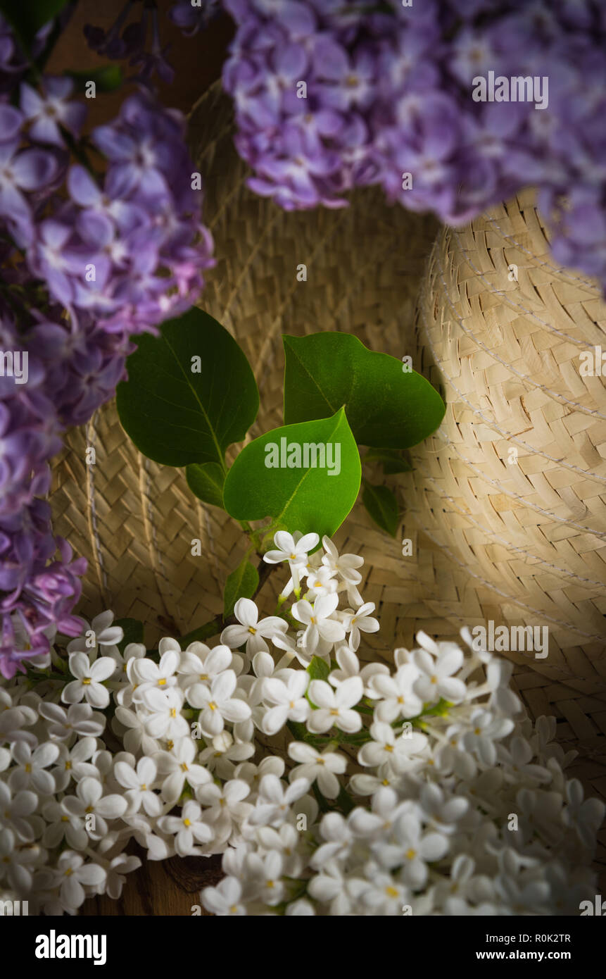 Still-life with a bouquet of lilacs and a straw hat, close-up Stock Photo