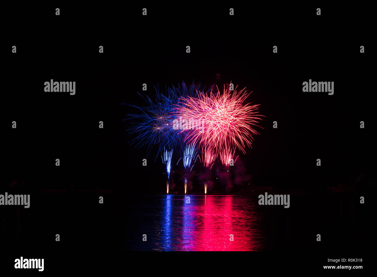 Red and blue rich stars from fireworks over surface of Brno's Dam with reflection on the surface of lake Stock Photo