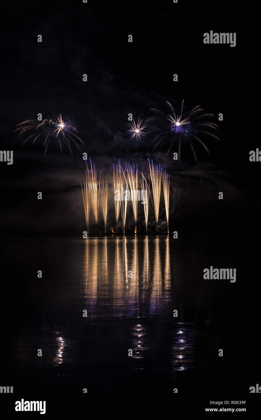 Gold and blue fountain in rich fireworks over surface of Brno's Dam with lake reflection Stock Photo