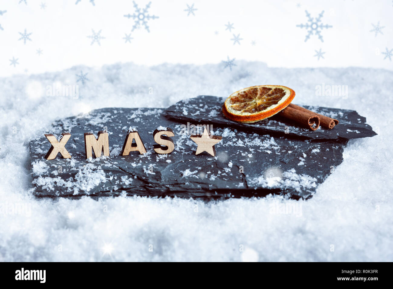 Christmas decoration of wooden XMAS letters, a slice of orange and cinnamon in the snow Stock Photo
