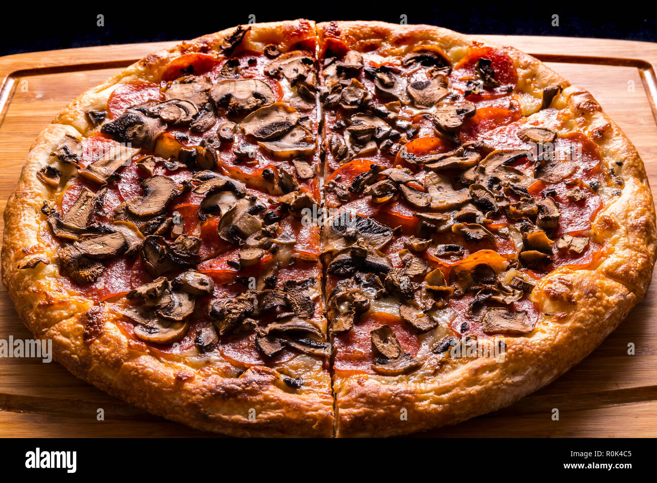 new york style pepperoni mushroom pizza on wooden cutting