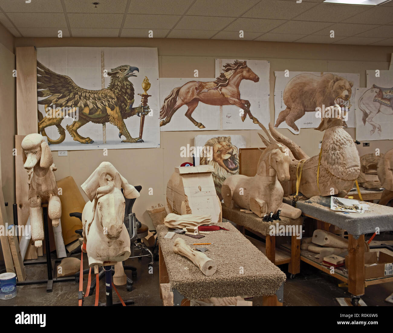 Carousel animals in the making. It's a long process as each one is carved by hand by master woodcarvers. Artist color renditions hang on the wall. Stock Photo